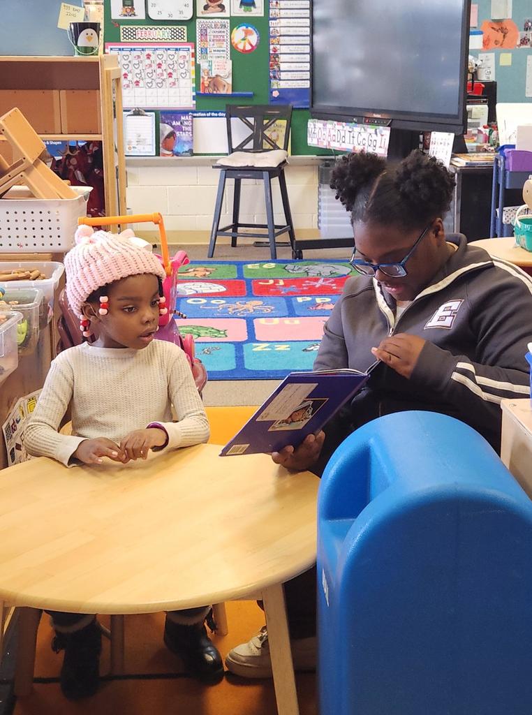 A student reading to a younger kid.