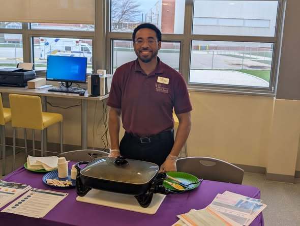 A man from the second harvest food bank is standing in front of food that is in a pan.