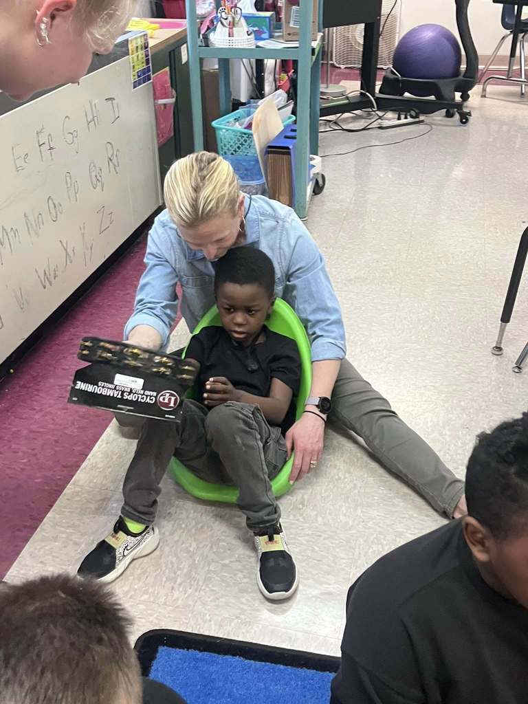 A student and teacher playing a tambourine. 