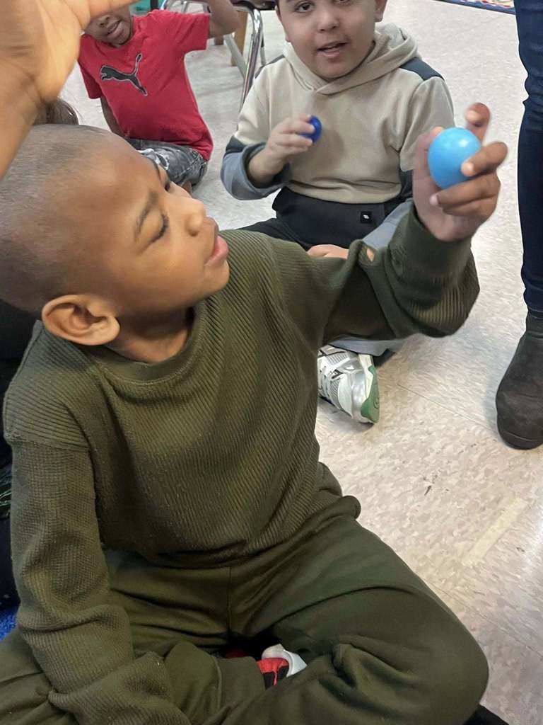 A student holding a blue plastic egg. 