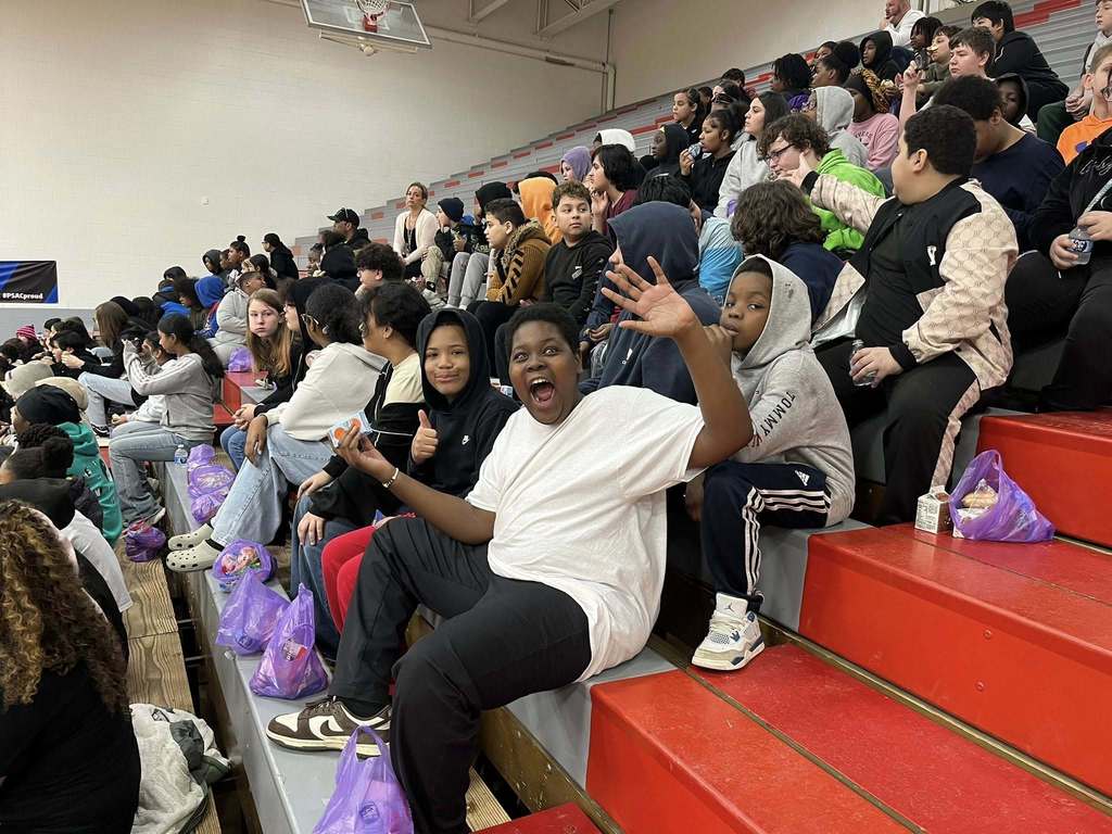 Students sitting on bleachers and smiling.