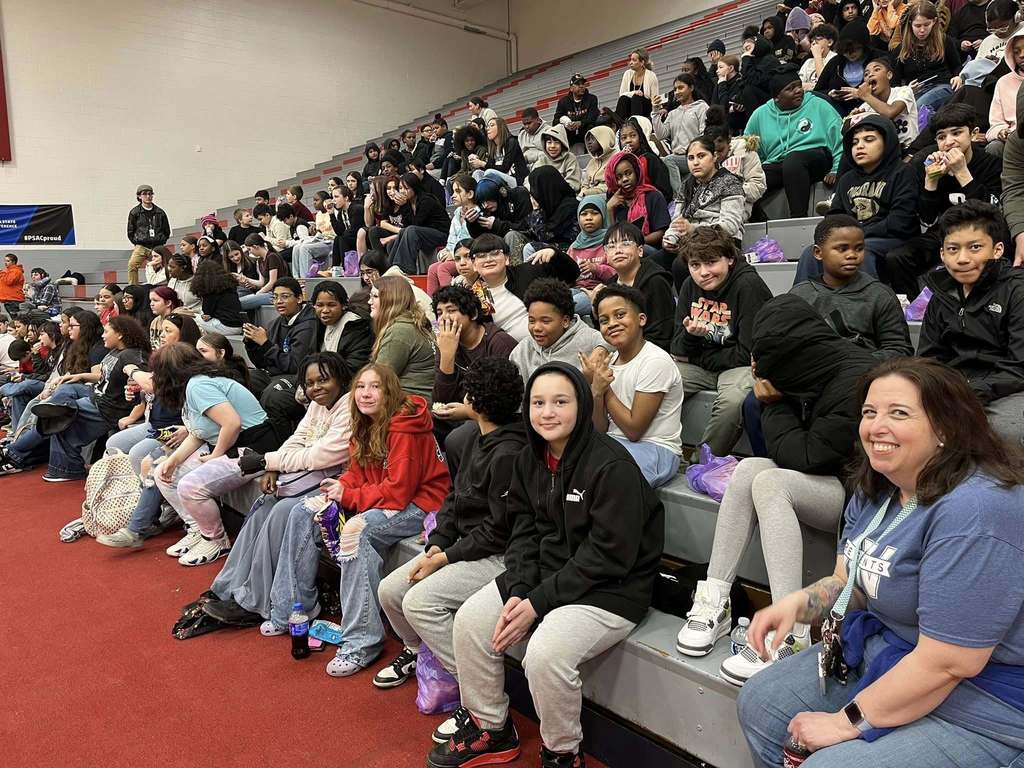 Students sitting on bleachers and smiling.