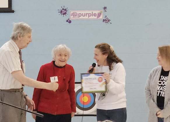 A women giving a certificate to two elderly individuals. 