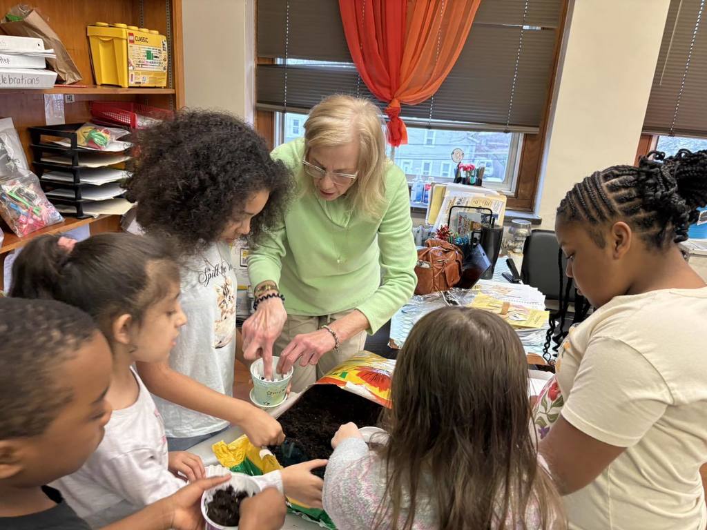 A women helping students put dirt in their containers. 