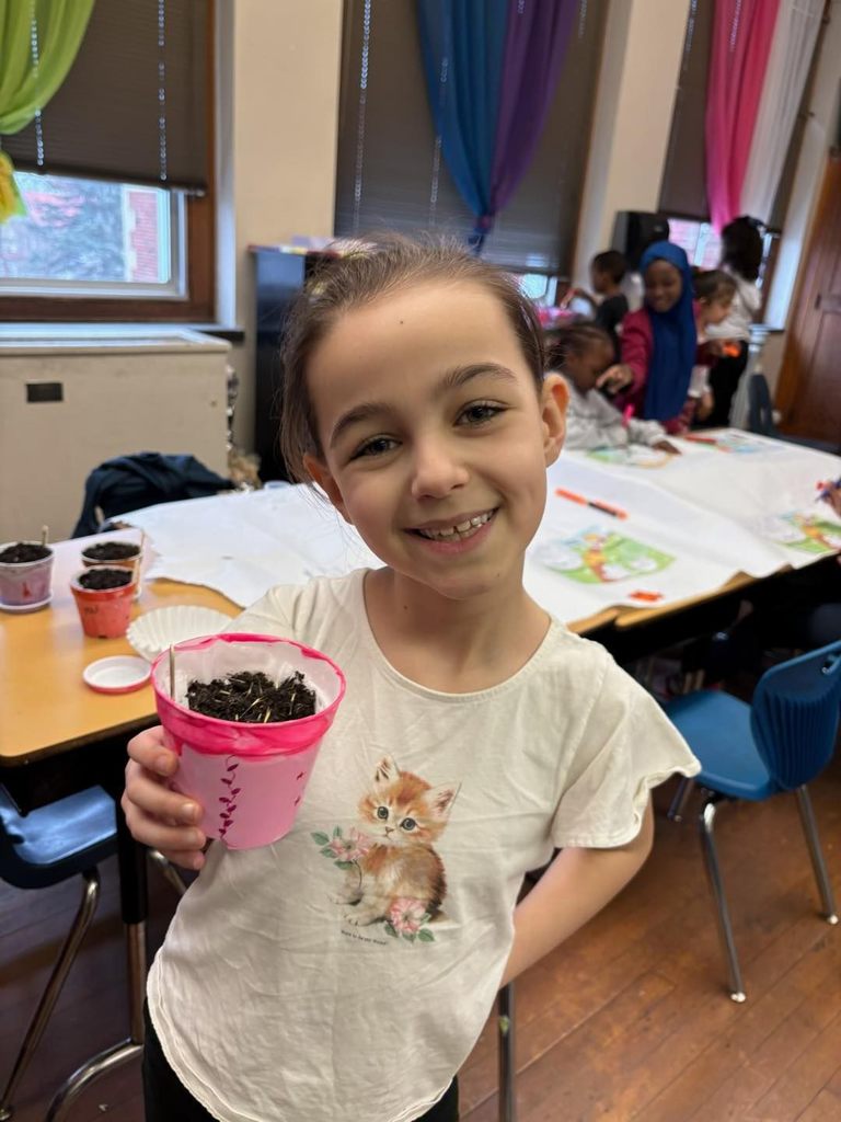 A young girl smiling while she holds her planter.