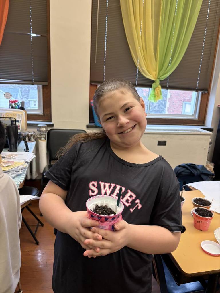 A young girl holding her planter and smiling. 
