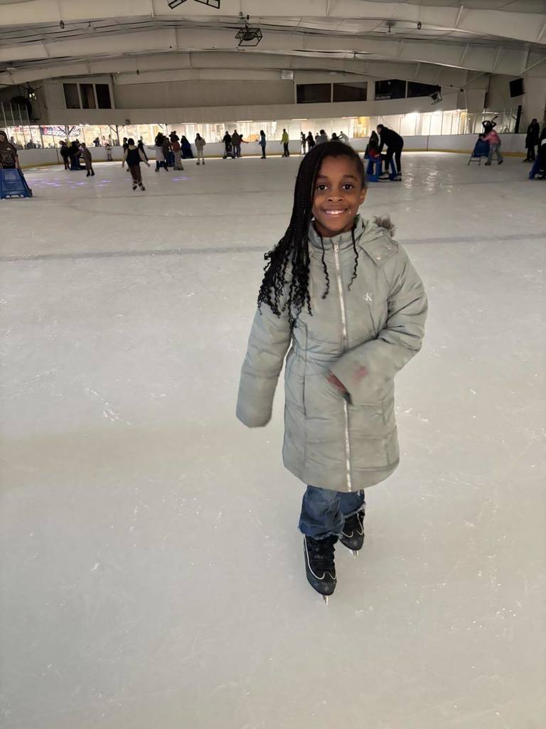 A young girl ice skating and smiling. 