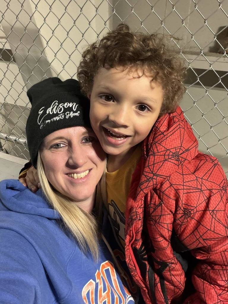 A student hugging a teacher and smiling. 