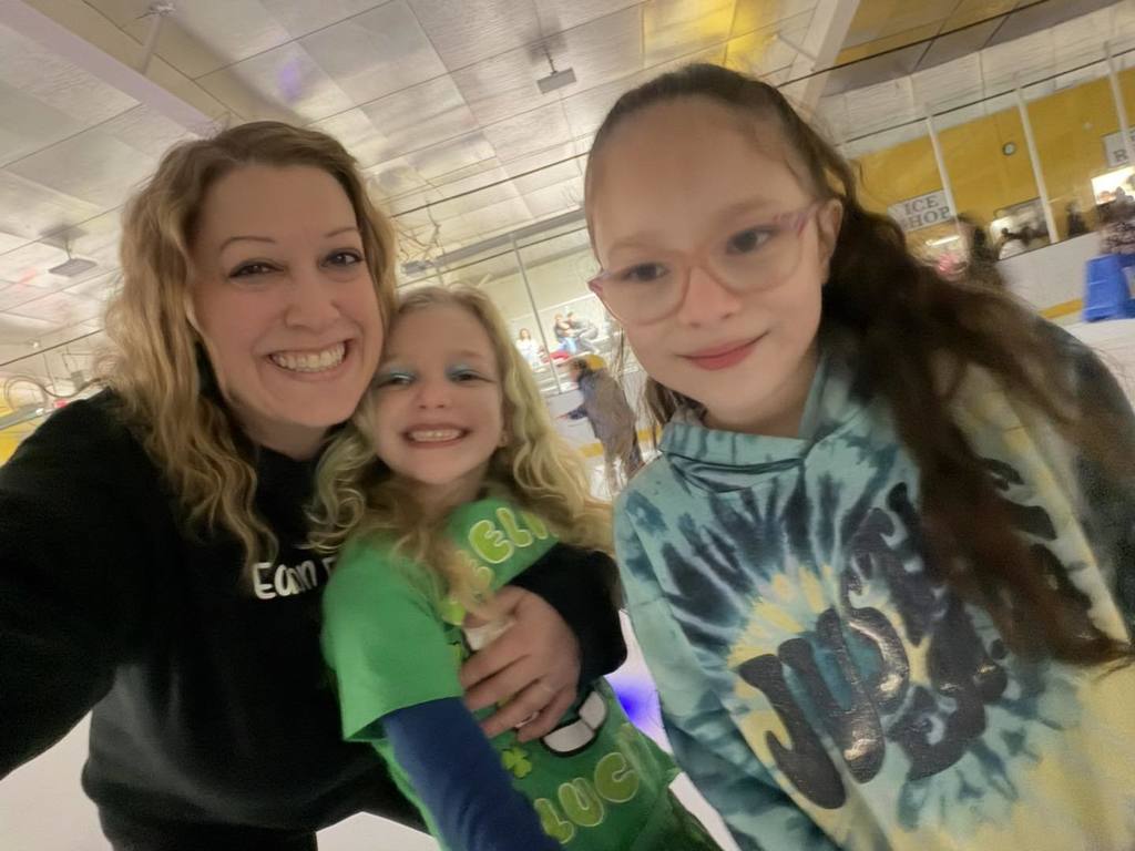 A teacher hugging her student and smiling.