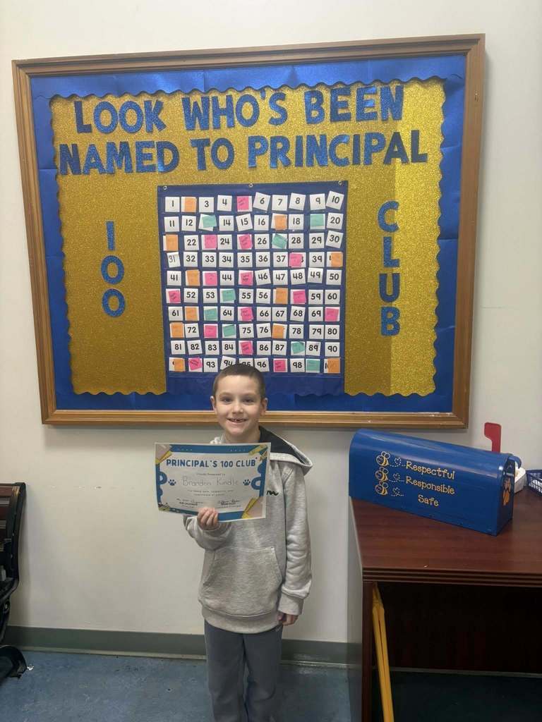 A student holding their "Principal 100 Club" certificate. 