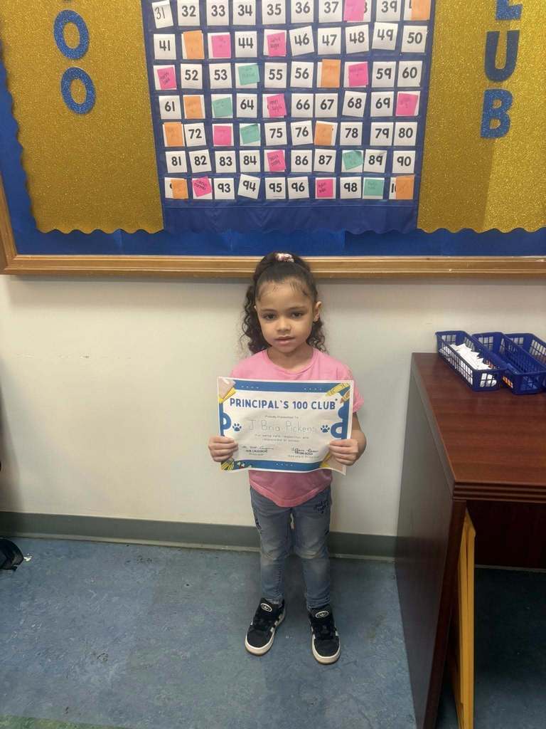 A student holding their "Principal 100 Club" certificate. 