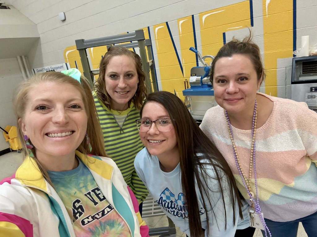 Teachers wearing bright 70s clothing and smiling. 