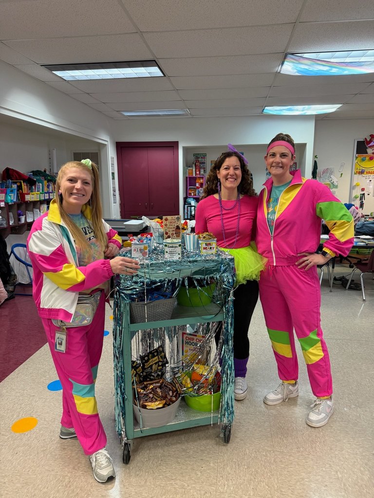 Teachers wearing bright 70s clothing and smiling. 