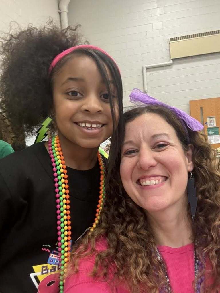 A teacher and student dressed like they are from the 80s and they are smiling. 