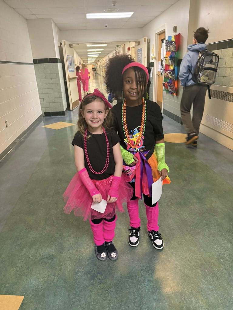 Two young girls dressed in bright 80s clothing. 