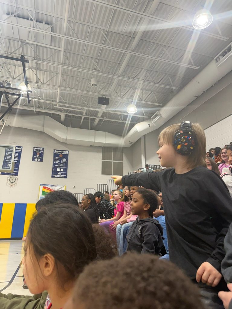 A student wearing headphones is pointing at something on the basketball court. 