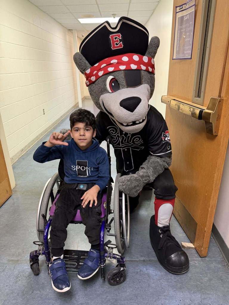 The Erie SeaWolves mascot kneeling next to a kid in a wheelchair. 