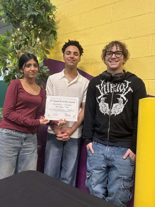 Students smiling as they hold a certificate they received.. 