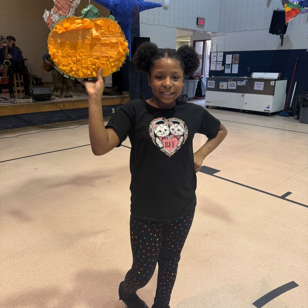 A young girl holding a pumpkin made of tissue paper. 