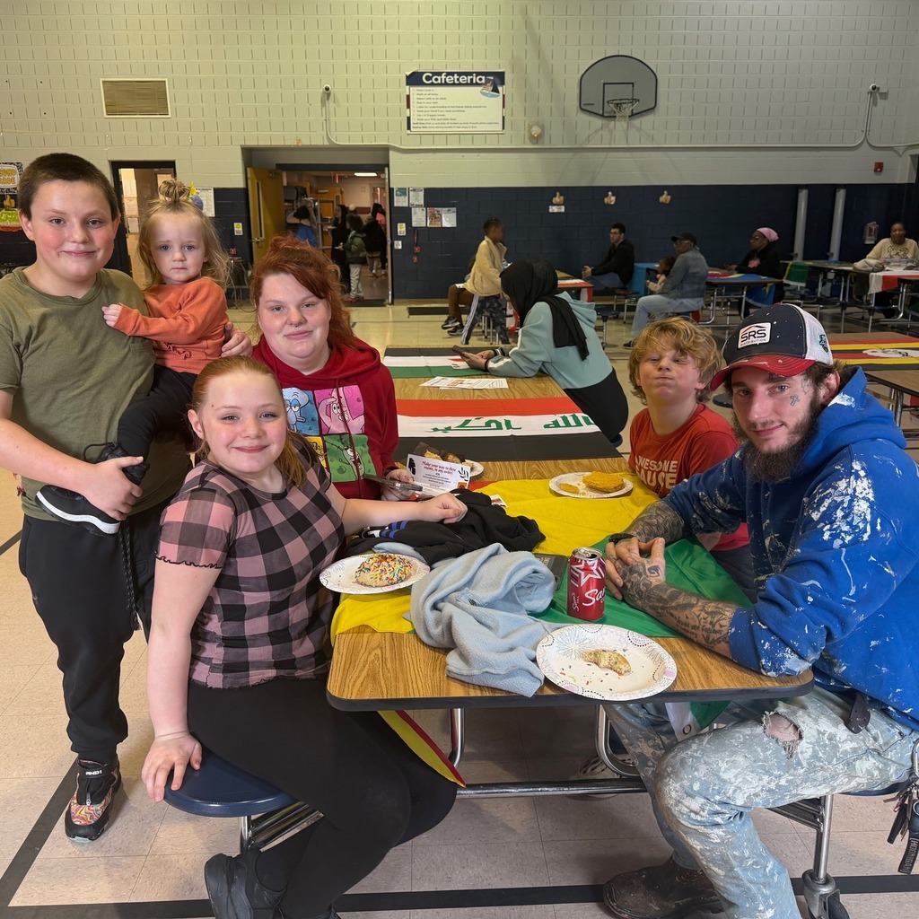A family eating at a long table in a school cafeteria. 