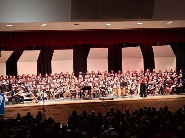 Students on stage playing instruments and singing. 
