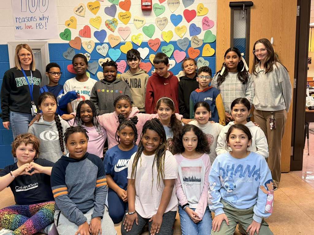 Students and teachers smiling in a hall. 