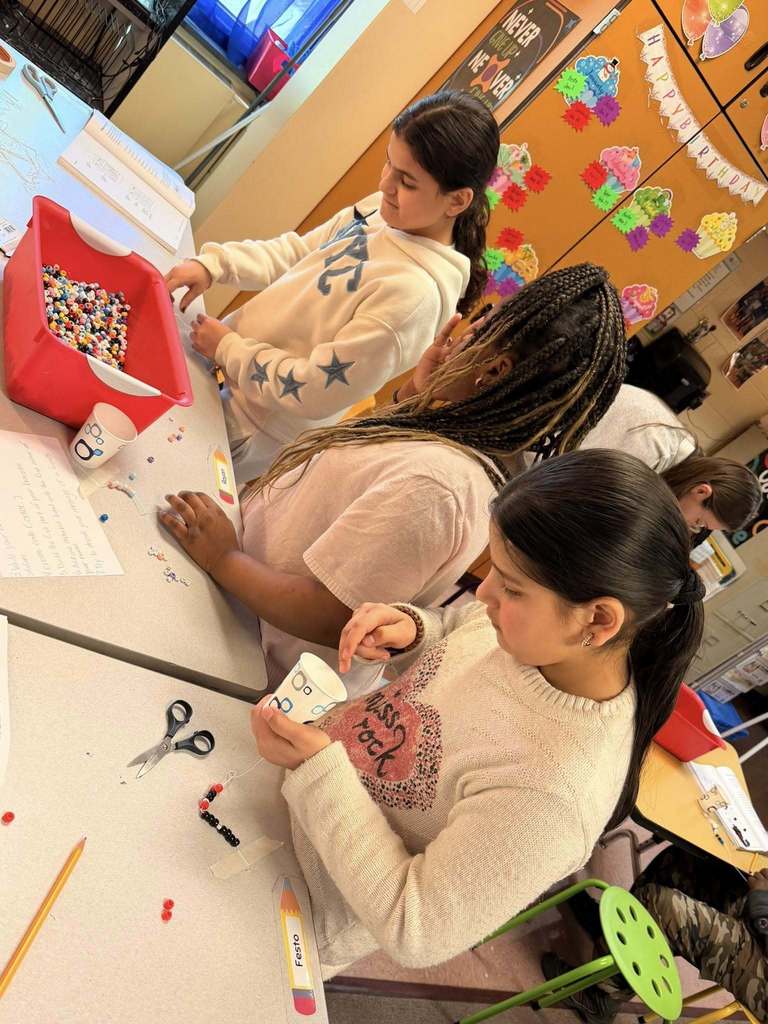 Students making bracelets using beads. 