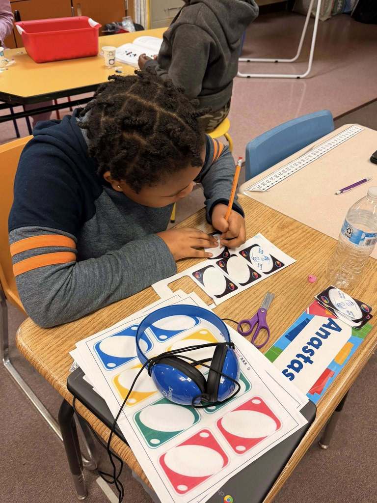 A student writing in the blank Uno cards that are printed on paper. 