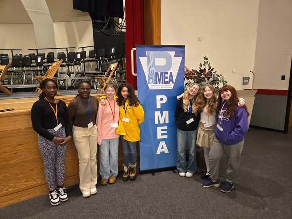 Students standing next to a blue PMEA sign. 