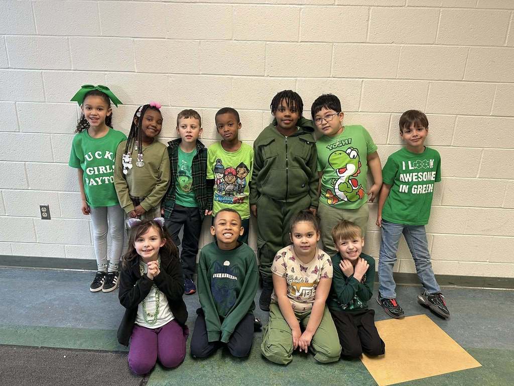 Students dressed in green and smiling. 