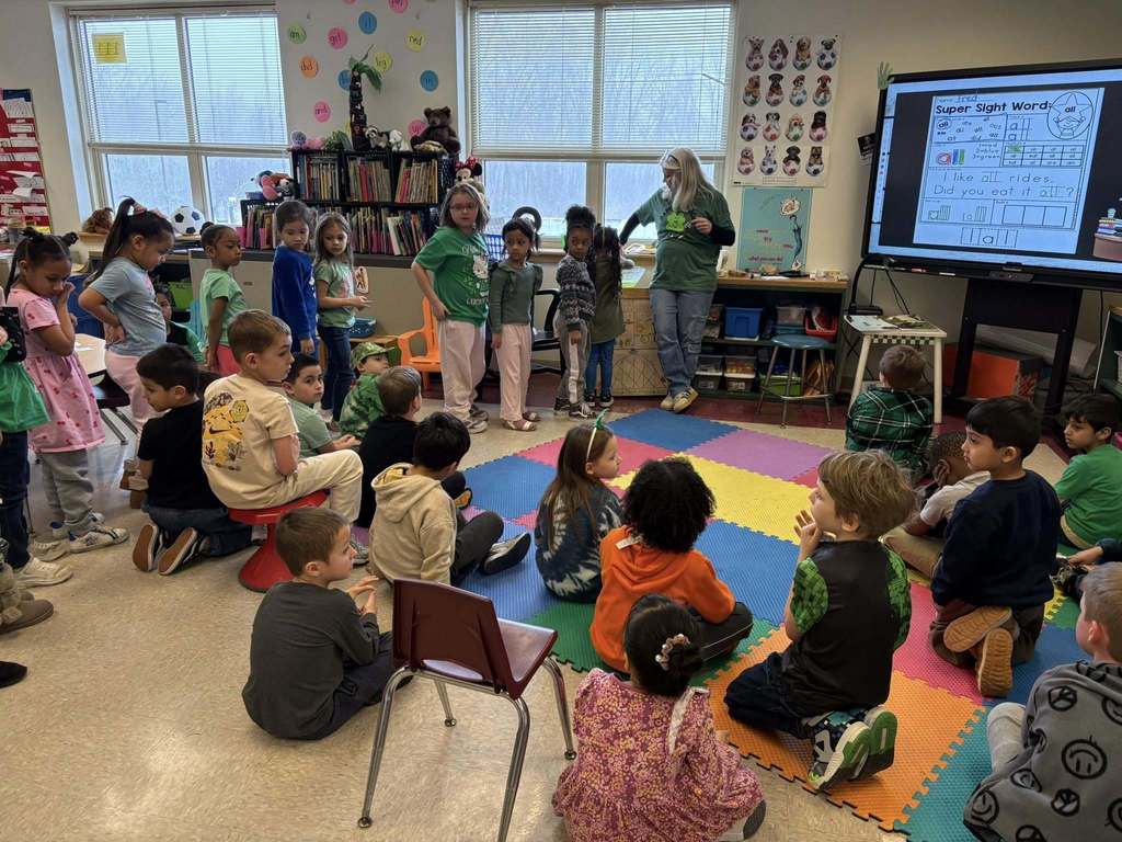 Students and a teacher dressed in green for St. Patrick's Day in a classroom. 