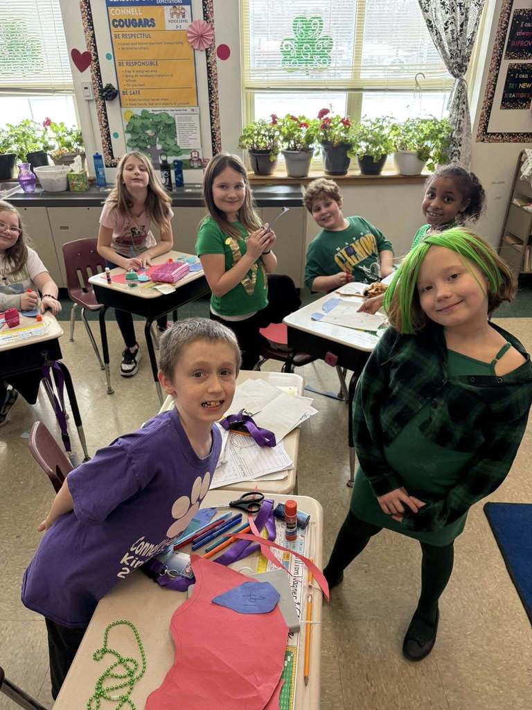 Students working on crafts and smiling in a classroom. 