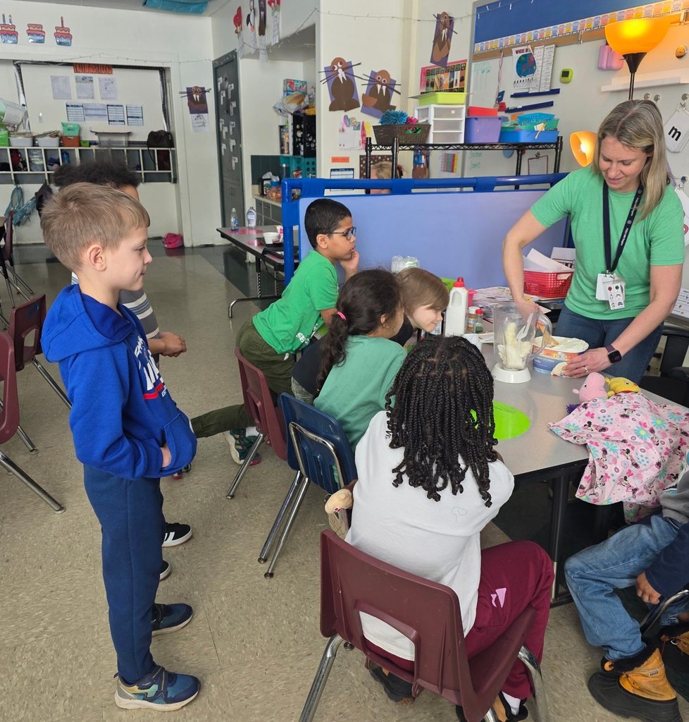 A teacher is adding ice cream to a blender while the students watch. 