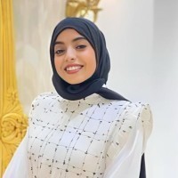 Young women wearing a hijab and white outfit smiling. 