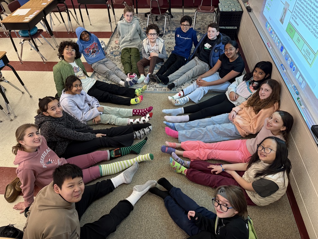 Students sitting in a circle smiling with mismatched socks on.