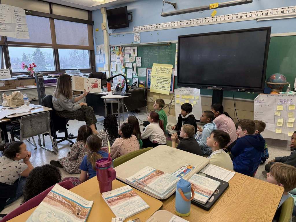 An adult reading to students in a classroom. 