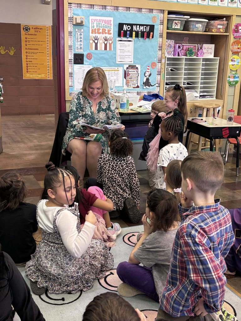 An adult reading to students in a classroom. 