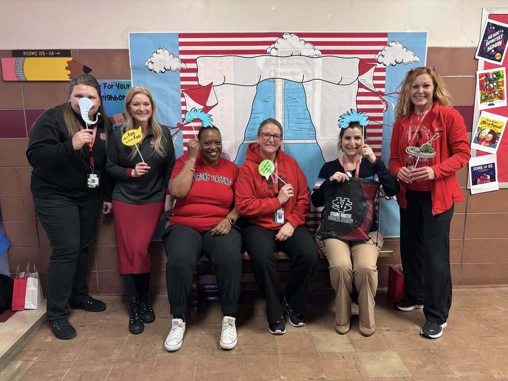 Adults wearing red and black while holding Dr. Suess props. 