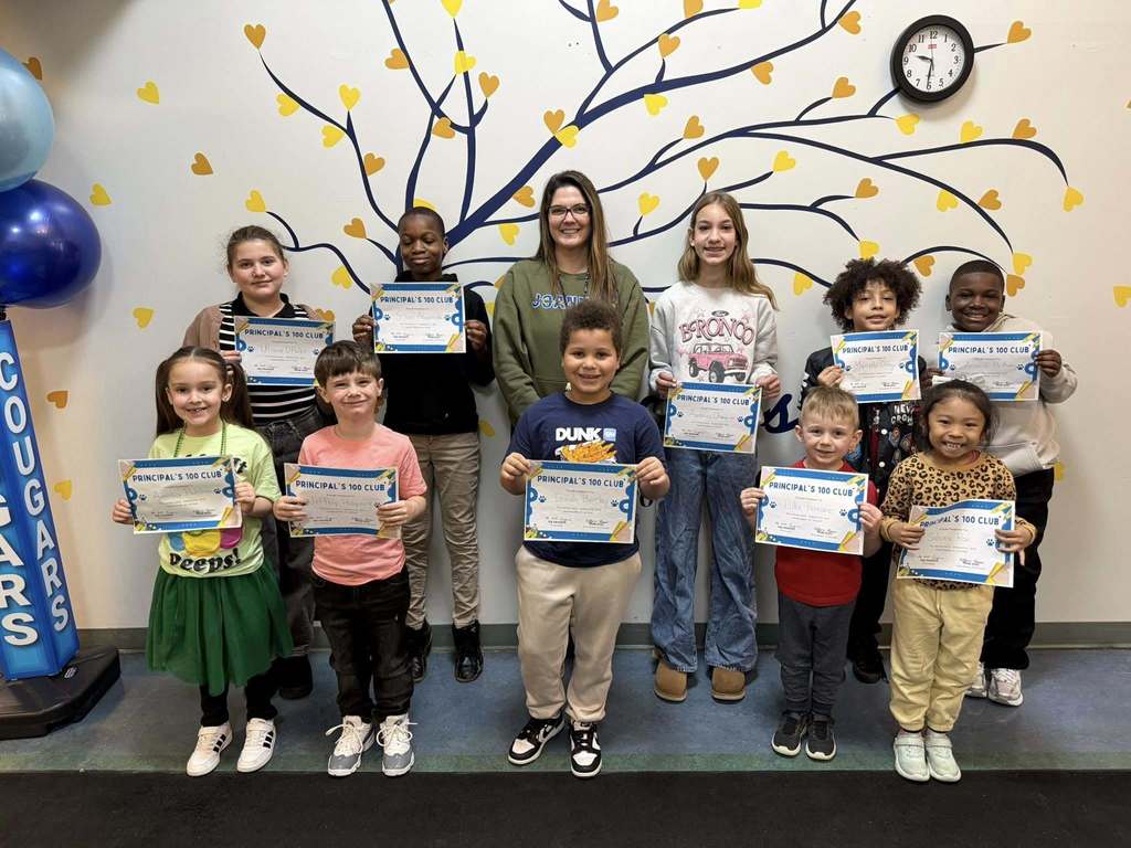 Students standing with a staff member and are holding their "Principal's 100Club" award.
