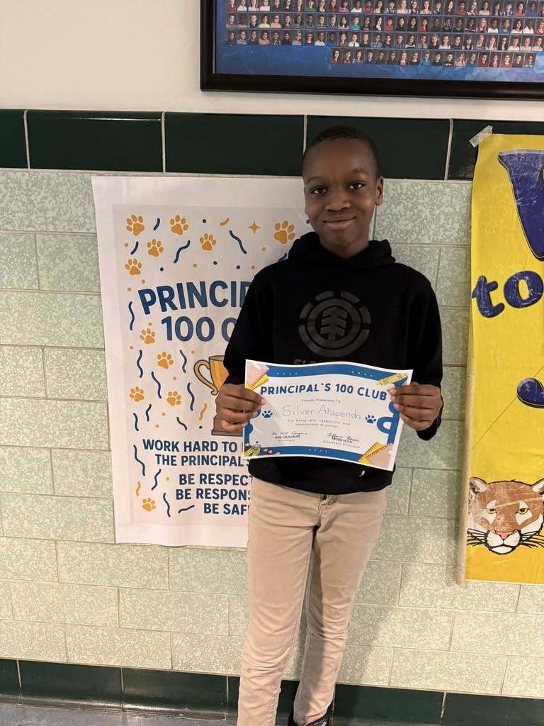 Young student wearing a black hoodie is holding his "Principal's 100 Club" Award. 