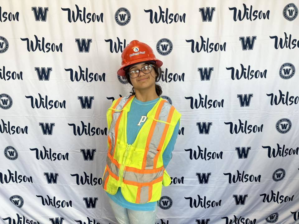 A student wearing National Fuel hard hats and vests while they smile.. 