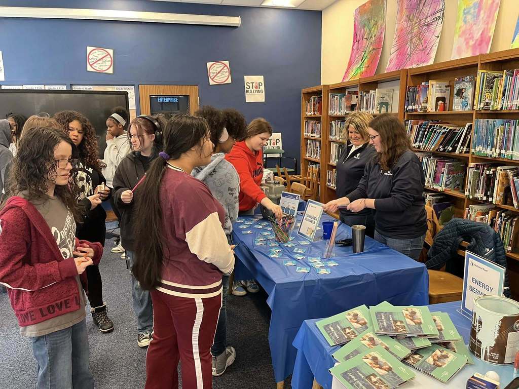 Students in a library talking to staff from National Fuel at a table. 