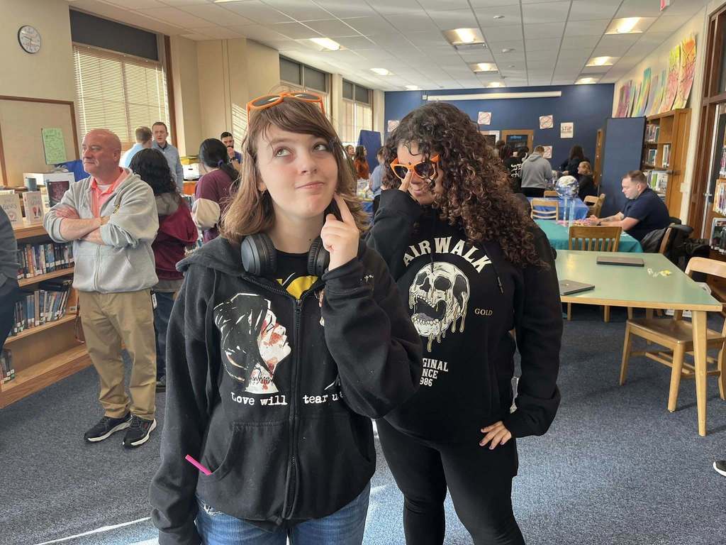 Two students wearing black hoodies posing for a photo in the library. 