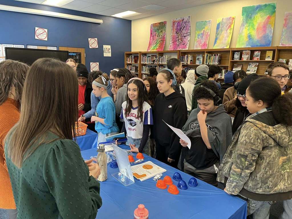 Students in a library talking to staff from National Fuel at a table. 
