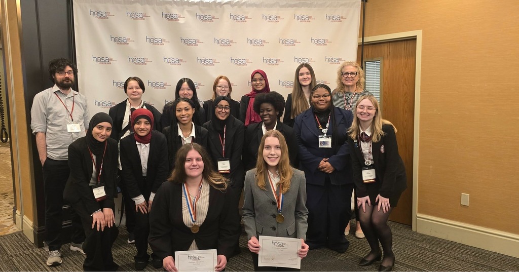 Teachers and a group of students who are holding their HOSA awards.