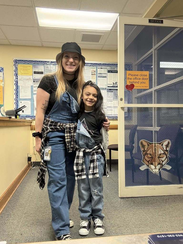 A teacher and student wearing denim overalls and a flannel tied around their waist for 90s day.  