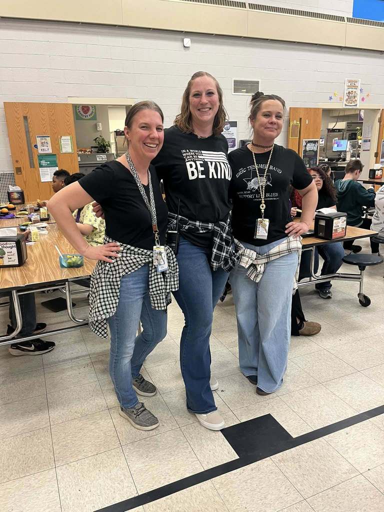 Three teachers wearing black shirts, jeans, and a flannel tied around their waist for 90s day. 
