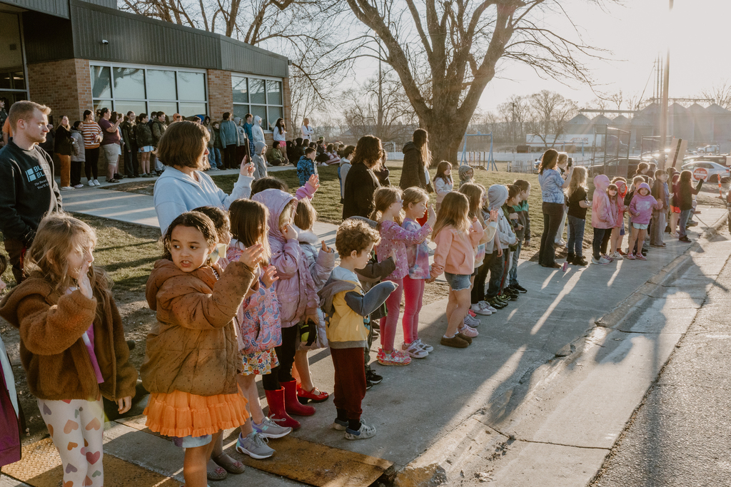 elementary kids waving at the tractors go by