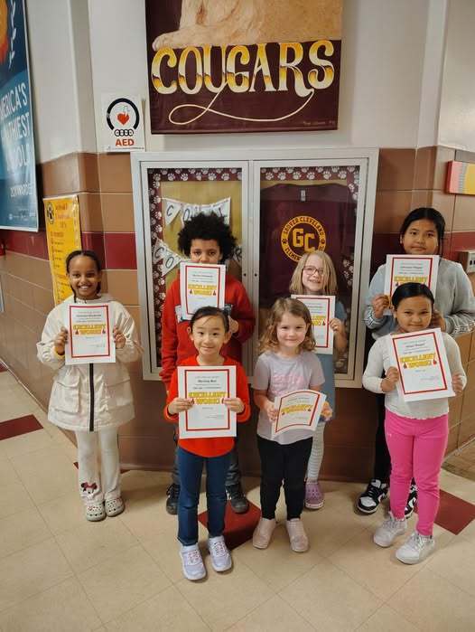 Students holding their Cool Cougars awards and smiling. 