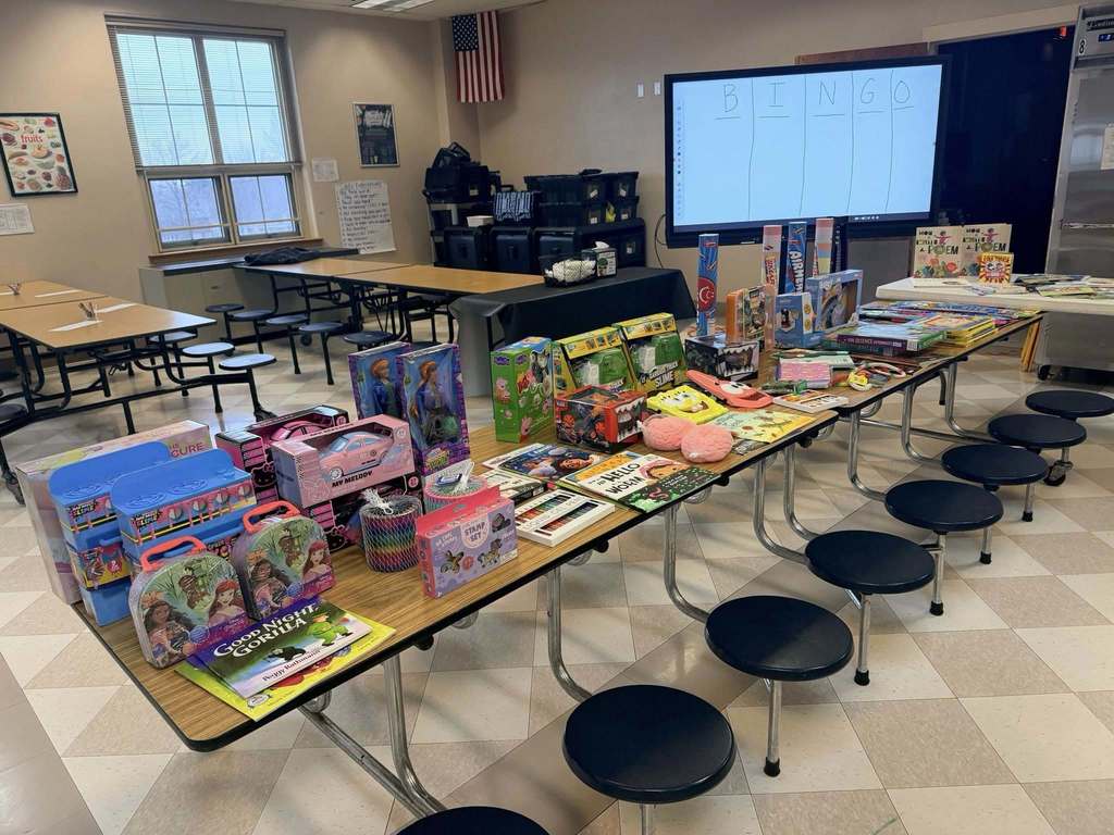 Toys and games on a long table in a school cafeteria. 